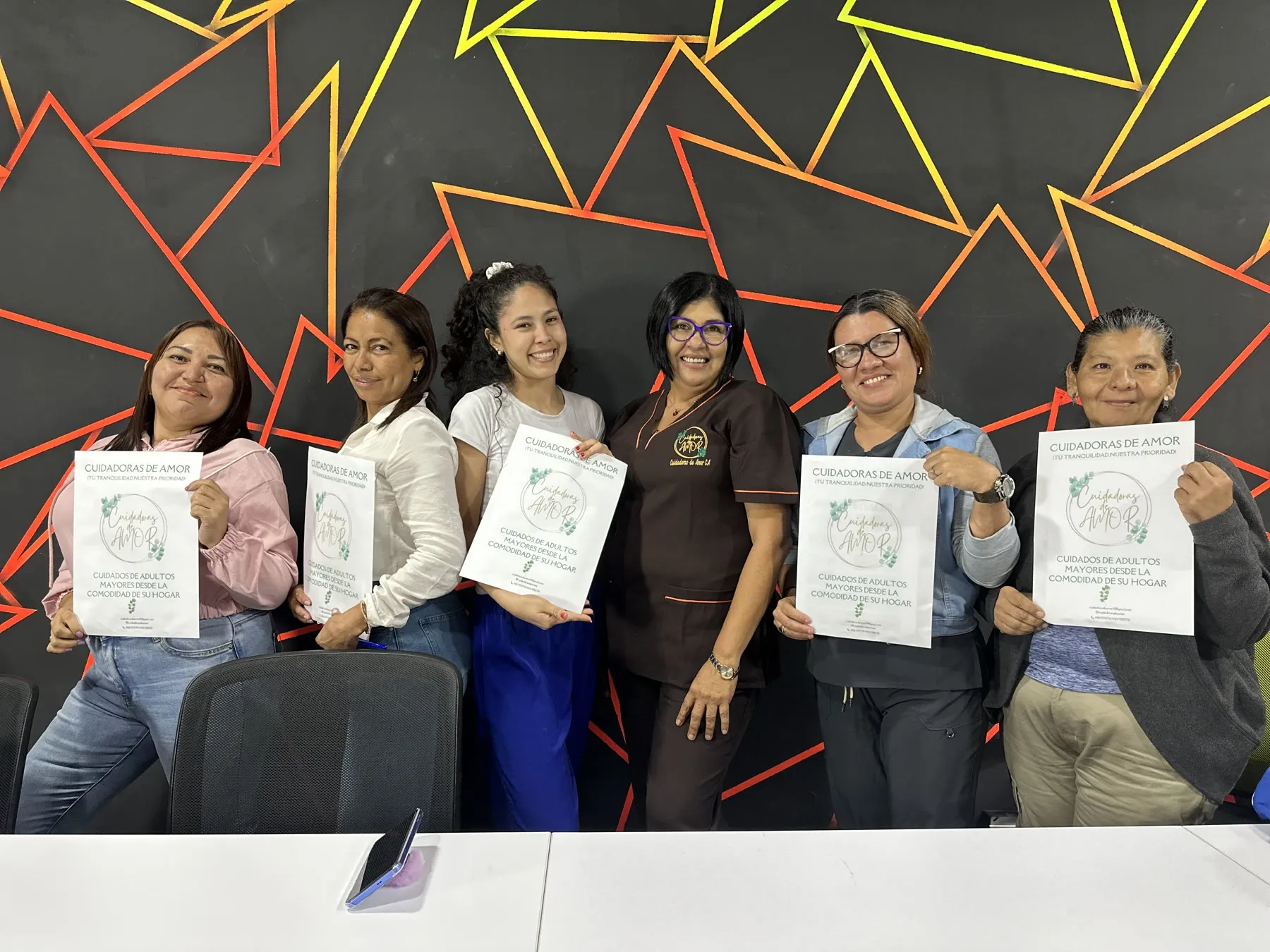 Mariela Arguelles junto a cuidadoras formadas en el taller El Faro del Cuidador, con sus certificados, en la sede de Caracas